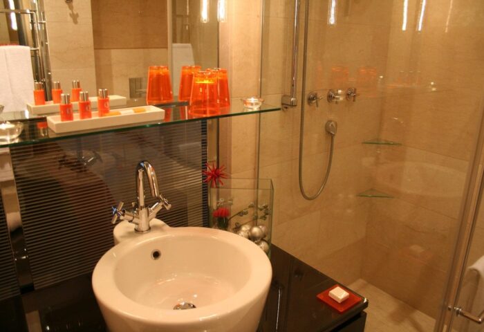 Bathroom at The Levante Parliament, a gay-friendly design hotel. Sink, shower, and orange accents create a stylish, adults-only space.