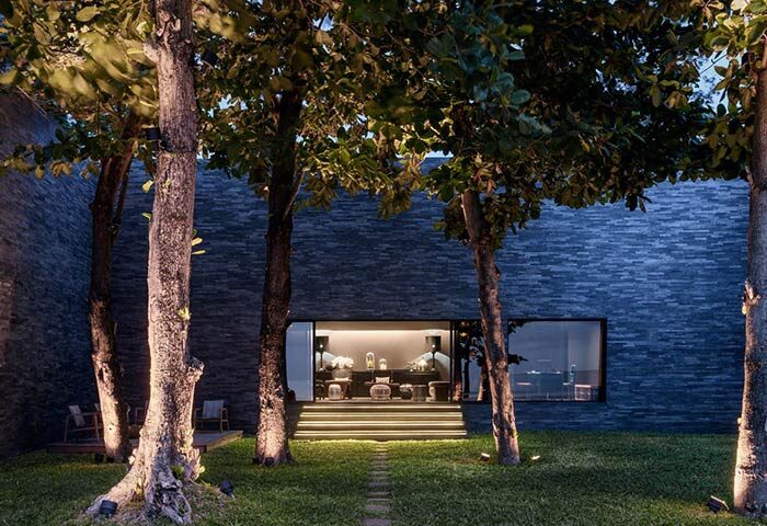 Exterior of The Library Hotel, a gay-friendly hotel. Lush trees frame the modern building with a welcoming, illuminated entrance.