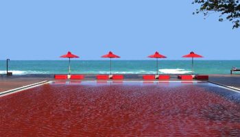 The Library Hotel pool view. Gay-friendly hotel with red pool, umbrellas, and beach. A unique gay travel destination.