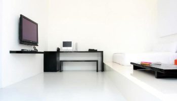 Minimalist room at The Library Hotel, a gay-friendly hotel. Features a desk, TV, and elevated bed platform. Modern design for gay travelers.
