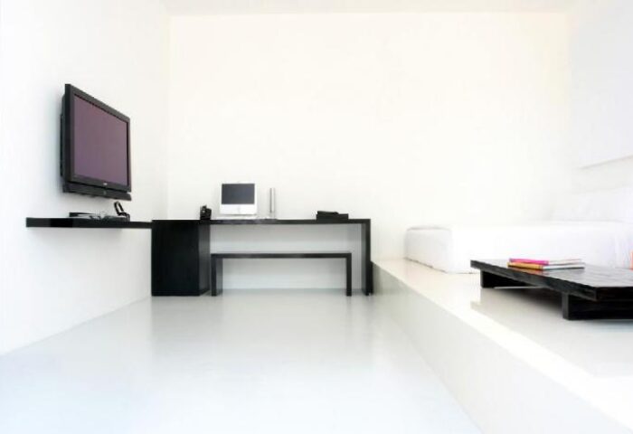 Minimalist room at The Library Hotel, a gay-friendly hotel. Features a desk, TV, and elevated bed platform. Modern design for gay travelers.
