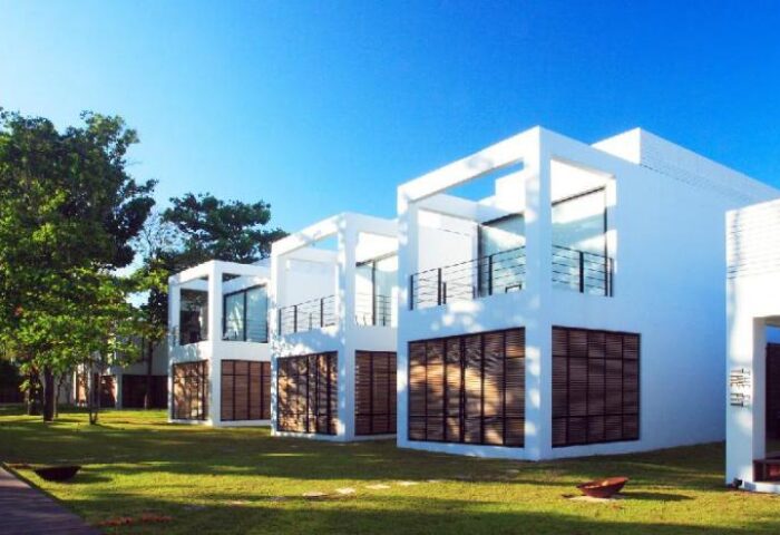 The Library Hotel, a gay-friendly hotel. Modern white buildings with balconies, set on green lawn under a clear blue sky.