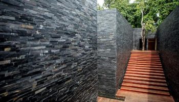 The Library Hotel's exterior: Stone walls and wooden steps lead to a doorway. Gay-friendly hotel with unique architecture and natural elements.