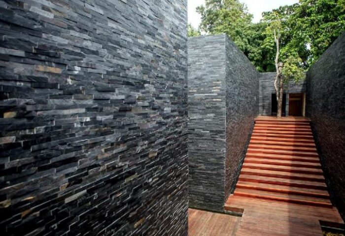 The Library Hotel's exterior: Stone walls and wooden steps lead to a doorway. Gay-friendly hotel with unique architecture and natural elements.