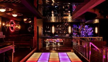 The LINQ Hotel and Casino gay-friendly bar. Dance floor with colorful lights, bar with bottles, and stylish decor. Gay travel advice.