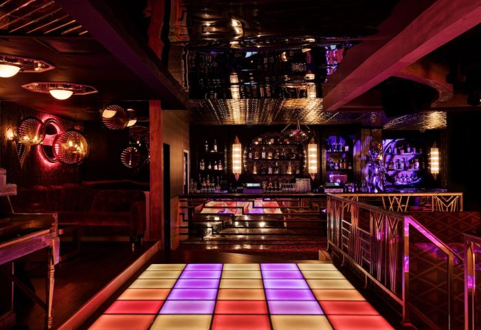 The LINQ Hotel and Casino gay-friendly bar. Dance floor with colorful lights, bar with bottles, and stylish decor. Gay travel advice.