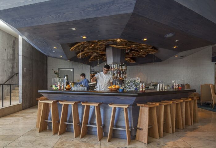 Bar at The Linq Hotel & Casino, a gay-friendly hotel. Bartenders, wooden stools, and a modern ceiling design create a stylish, welcoming vibe.