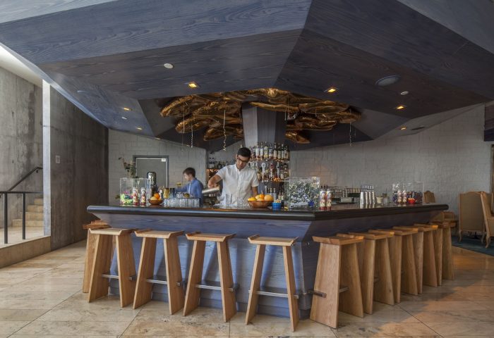 Bar at The Linq Hotel & Casino, a gay-friendly hotel. Bartenders, wooden stools, and a modern ceiling design create a stylish, welcoming vibe.