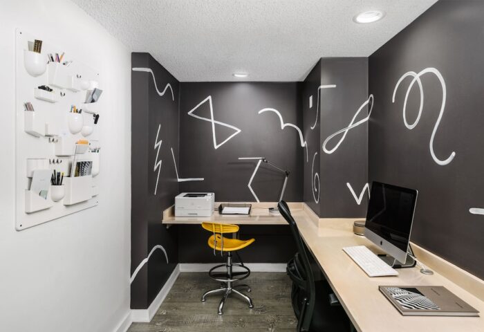The Linq Hotel & Casino's workspace: Desk, computer, yellow chair, and wall art. A gay-friendly hotel with modern design elements.