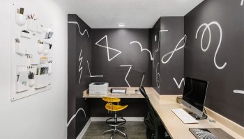 The Linq Hotel & Casino's workspace: Desk, computer, yellow chair, and wall art. A gay-friendly hotel with modern design elements.