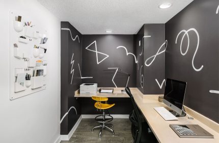 The Linq Hotel & Casino's workspace: Desk, computer, yellow chair, and wall art. A gay-friendly hotel with modern design elements.
