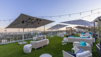 The London West Hollywood at Beverly Hills gay-friendly hotel rooftop. Lounge seating, umbrellas, city view, and string lights.