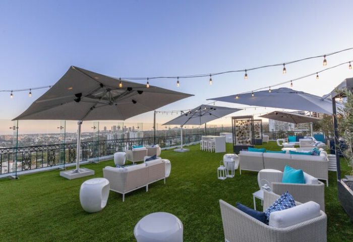 The London West Hollywood at Beverly Hills gay-friendly hotel rooftop. Lounge seating, umbrellas, city view, and string lights.