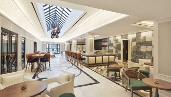 The London West Hollywood at Beverly Hills gay-friendly hotel lounge. Bar seating, tables, and chairs under a skylight. Upscale, modern design.