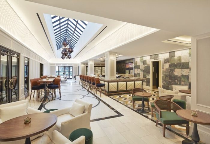 The London West Hollywood at Beverly Hills gay-friendly hotel lounge. Bar seating, tables, and chairs under a skylight. Upscale, modern design.