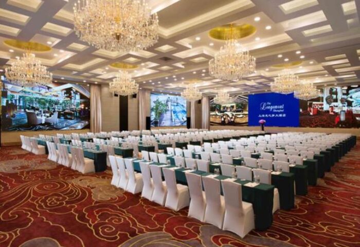 The Longemont Shanghai Hotel ballroom. Gay-friendly hotel event space with chandeliers, screens, and rows of tables and chairs.