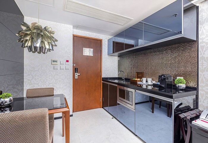 The Mercer Hong Kong, a gay-friendly hotel. Kitchenette with mirrored cabinets, dining table, and modern lighting. Upscale design.