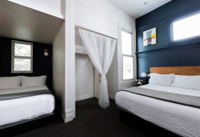 The Metro Hotel gay-friendly room. Two beds, dark walls, white linens. Closet with sheer curtain. Comfortable stay for gay travelers.