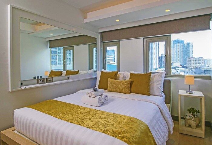The Mini Suites Eton Tower Makati gay-friendly hotel room. Bed, city view, mirror, and modern decor for gay travelers in Makati, Philippines.