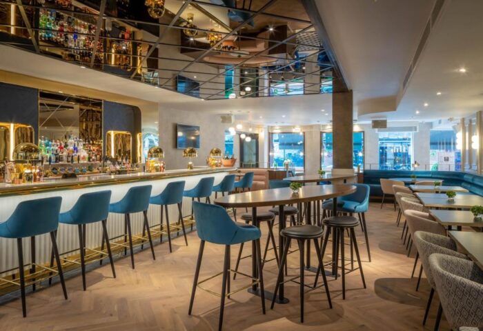 Interior of The Morgan Hotel, a gay-friendly hotel. Bar with blue stools, tables, and seating areas. Chic design for gay travelers.
