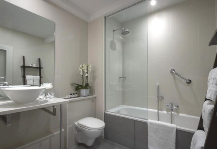 The Morgan Hotel bathroom. Modern design with sink, toilet, bathtub with glass, and orchid. Gay-friendly hotel for gay men travel advice.