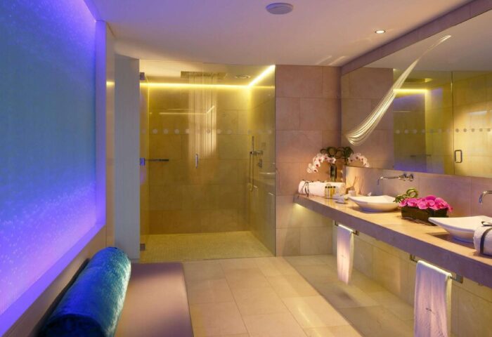 The Morrison, a DoubleTree by Hilton Hotel gay-friendly bathroom. Shower, double sinks, and bench with blue lighting. Upscale design.