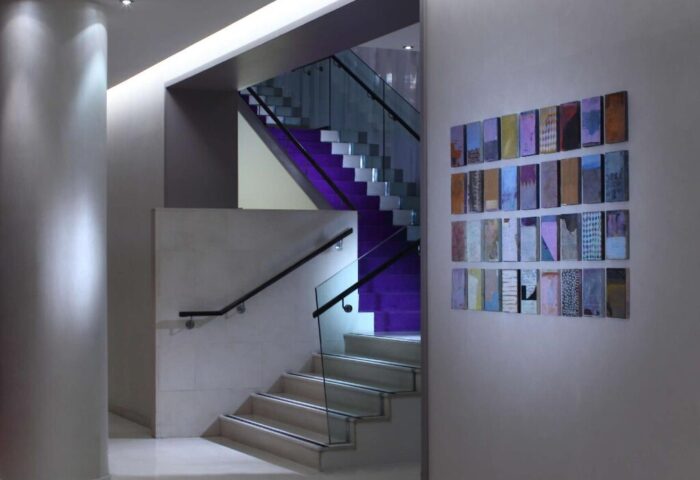 The Morrison, a DoubleTree by Hilton Hotel stairs. Gay-friendly hotel with modern design, glass railings, and purple accents. Column and art on wall.