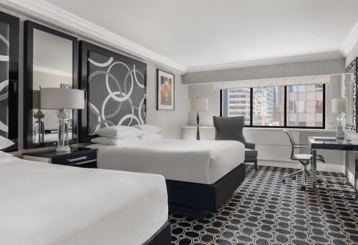 The Muse New York hotel room. Gay-friendly hotel featuring two beds, a desk, and a view of the city skyline. Interior design.