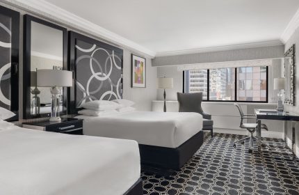 The Muse New York hotel room. Gay-friendly hotel featuring two beds, a desk, and a view of the city skyline. Interior design.