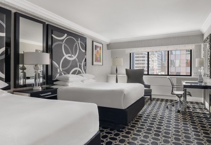 The Muse New York hotel room. Gay-friendly hotel featuring two beds, a desk, and a view of the city skyline. Interior design.