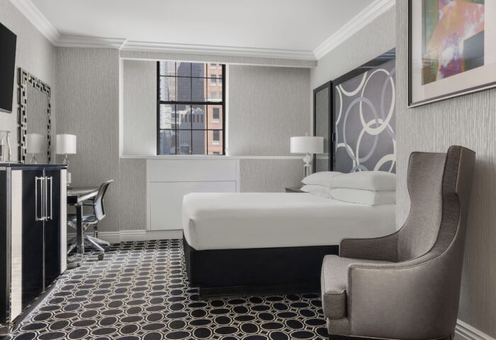 The Muse New York, a gay-friendly hotel: Guest room interior with bed, chair, desk, and city view. Modern design for gay travel.