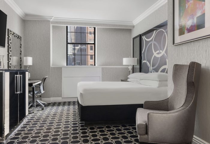 The Muse New York, a gay-friendly hotel: Guest room interior with bed, chair, desk, and city view. Modern design for gay travel.