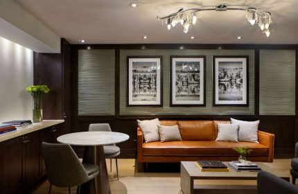 The Muse New York, a gay-friendly hotel. Lounge area with leather couch, table, and art. Perfect for gay travel in NYC.