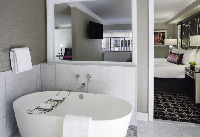 The Muse New York, a gay-friendly hotel. Bathroom with tub, bedroom view. Modern design for gay men travelers in NYC.