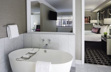 The Muse New York, a gay-friendly hotel. Bathroom with tub, bedroom view. Modern design for gay men travelers in NYC.