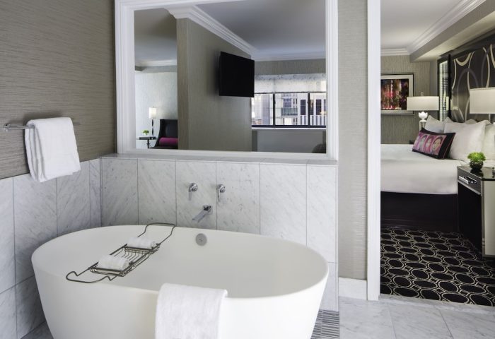 The Muse New York, a gay-friendly hotel. Bathroom with tub, bedroom view. Modern design for gay men travelers in NYC.