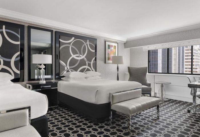The Muse New York, a gay-friendly hotel. Room with two beds, patterned headboards, city view. Stylish lodging for gay travelers.