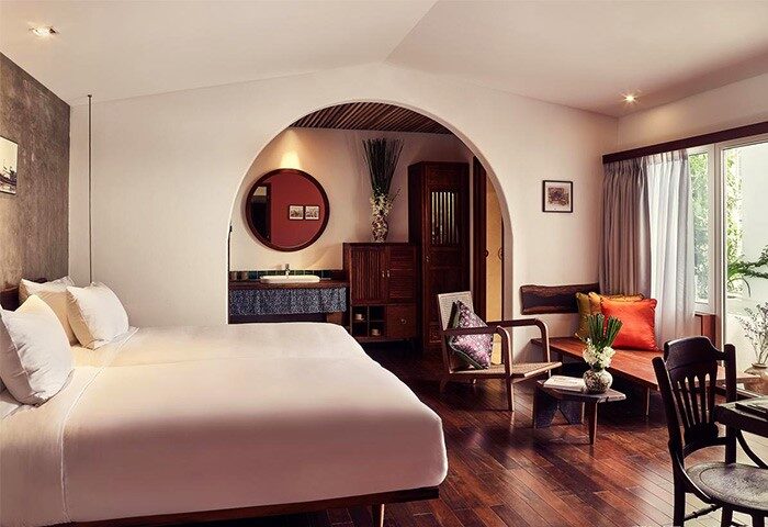 The Myst Dong Khoi hotel room. Gay-friendly travel in Ho Chi Minh City. Interior with bed, sink, chairs, and balcony. Stylish design.