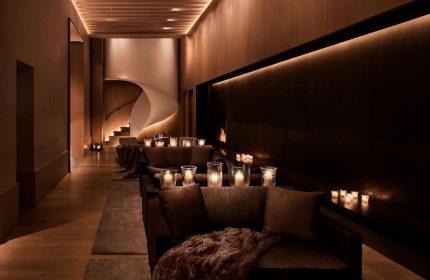 The New York EDITION, a gay-friendly hotel. Lounge area with candles, fireplace, and spiral staircase. Luxury travel for gay men.