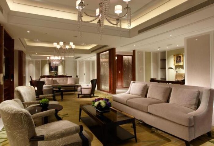 The Okura Prestige Taipei Hotel suite lounge area. Gay-friendly hotel with luxury seating, chandelier, and tables. Taipei travel advice.