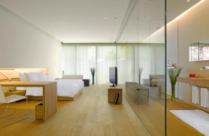 The Opposite House Hotel room. Gay-friendly hotel bedroom with bed, desk, TV, and glass-enclosed bathroom. Modern design.