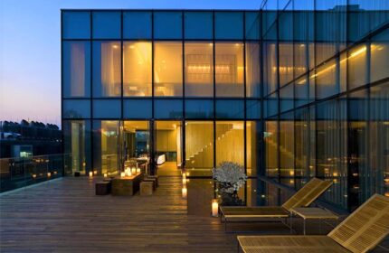 The Opposite House Hotel: Modern architecture, glass facade, and wooden deck with lounge chairs. Gay-friendly hotel design with outdoor space.