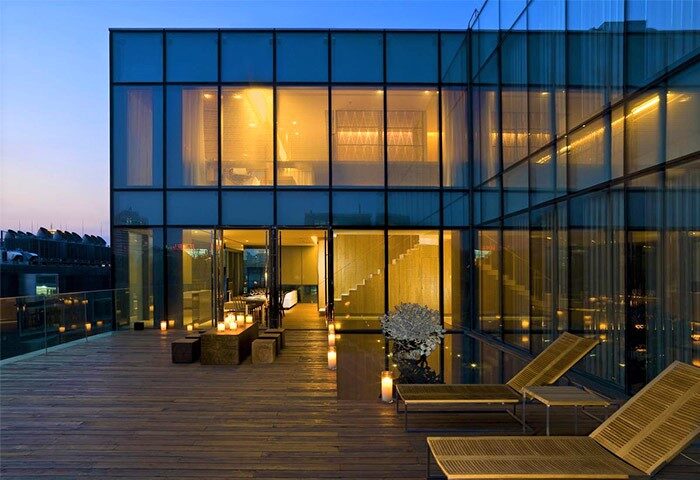 The Opposite House Hotel: Modern architecture, glass facade, and wooden deck with lounge chairs. Gay-friendly hotel design with outdoor space.