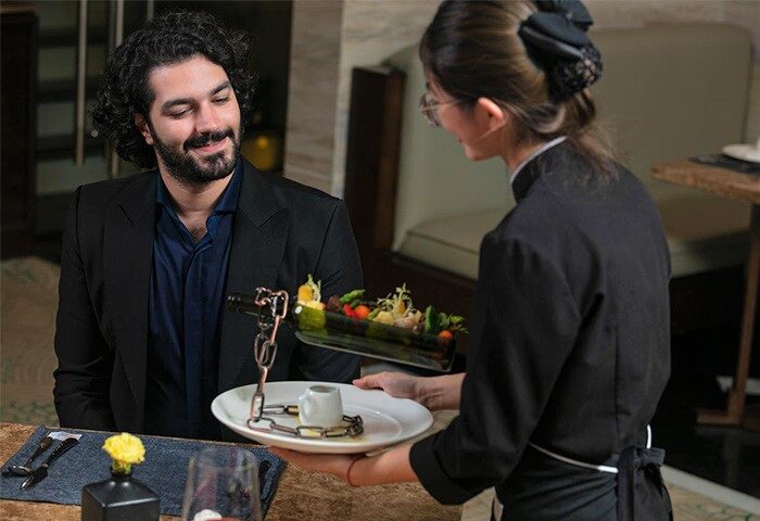Gay-Friendly Hotel: The Oriental Jade Hotel dining. Waitress serves a stylish salad to a guest. Fine dining experience.