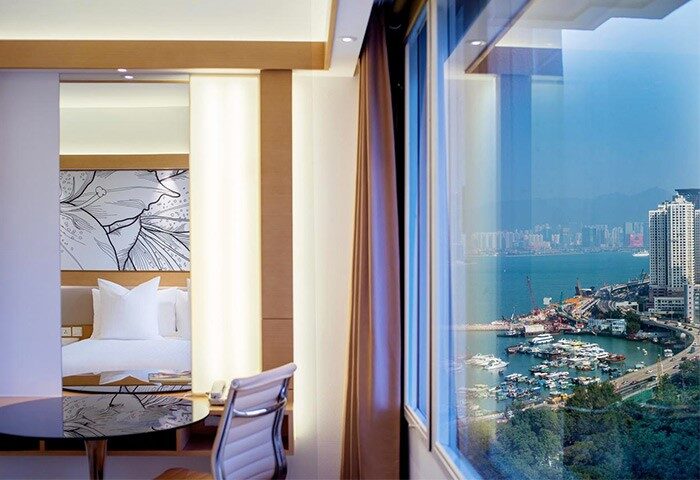 Gay-friendly The Park Lane Hong Kong a Pullman Hotel room with harbor view. Modern decor, desk, and bed. Ideal for gay travelers' comfort.