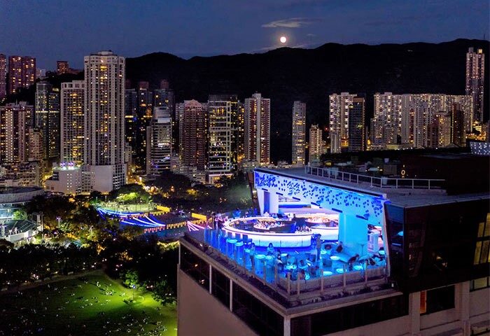 The Park Lane Hong Kong a Pullman Hotel rooftop bar at night. Gay-friendly hotel with city views, mountains, and a full moon.