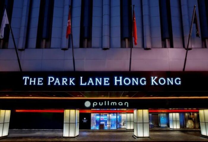 The Park Lane Hong Kong a Pullman Hotel entrance. Gay-friendly hotel in Hong Kong. Flags, illuminated signage, and modern architecture.