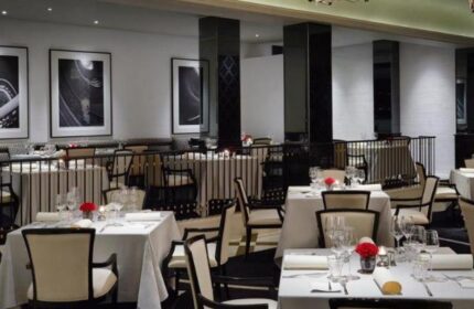 Elegant dining room at The Peninsula Manila, a gay-friendly hotel. Tables set with fine linens and glassware. Black and white decor.