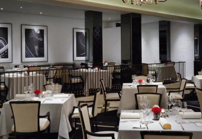 Elegant dining room at The Peninsula Manila, a gay-friendly hotel. Tables set with fine linens and glassware. Black and white decor.