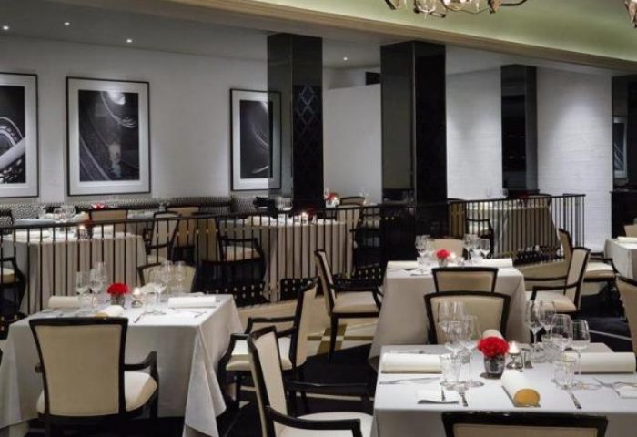 Elegant dining room at The Peninsula Manila, a gay-friendly hotel. Tables set with fine linens and glassware. Black and white decor.